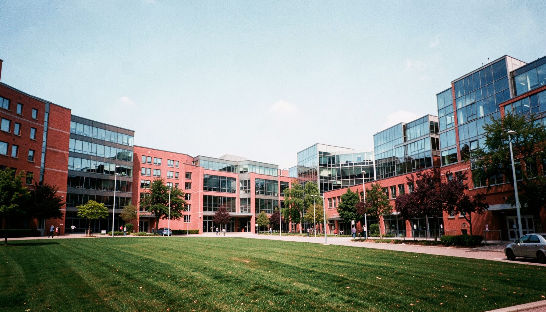 Wide-angle view of the University of Limerick campus on a bright day, green lawns and modern glass buildings under soft sunlight